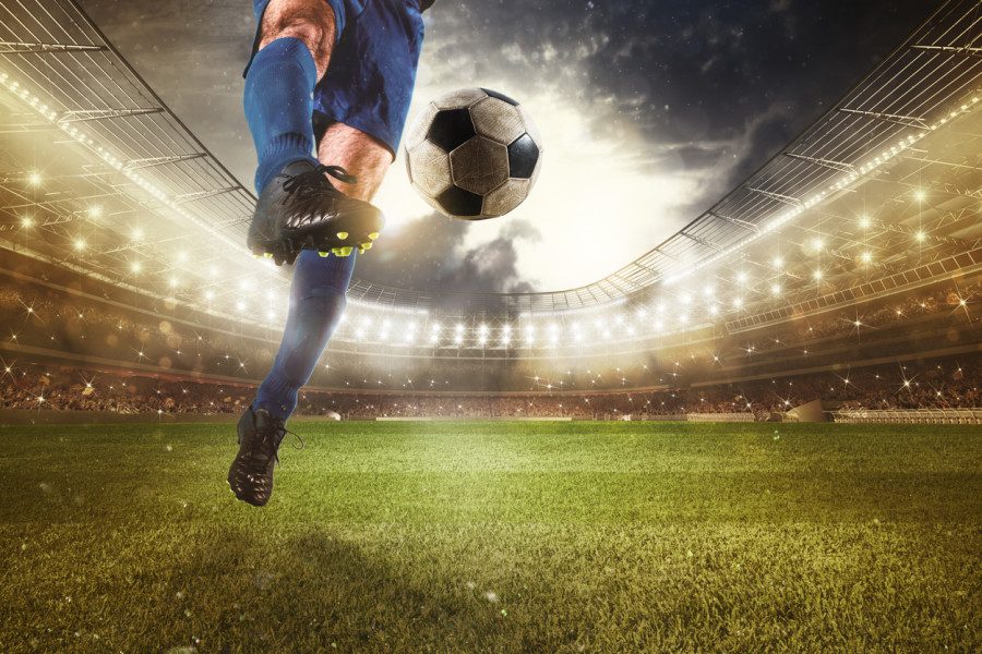 Football player kicking a ball in a stadium